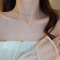 Close-up of a double-layered gold necklace featuring a pearl pendant on a model - Gold Beads