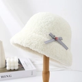 Close-up detail of a white fuzzy bucket hat with a stylish grey bow and button accent - Cream