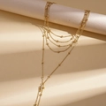 Dettaglio della collana dorata multistrato con pendente a croce in zircone e perline - Oro