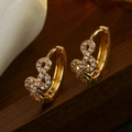 Gold plated infinity hoop earrings with clear cubic zirconia on a dark wood background - Infinity Symbol Style