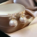 Dettaglio macro di orecchini a fiocco dorati con pavé di cristalli e perla - Champagne (Stile Fiocco)