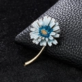 Elegant gold daisy brooch with blue and white enamel petals on a black leather background - XD9417-3 Blue Daisy