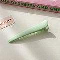 Matte light green bobby pin with minimalist curved design on textured background - Green