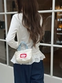Quilted white crossbody bag with denim handles shown on model in a casual street setting - Creamy White