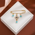 Golden safety pin brooch with sparkling rhinestone cross and blue evil eye charms - Cross Evil Eye Style (Z300)