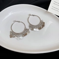 Dettaglio di orecchini a cerchio in argento con nappe di paillettes tonde su piatto - Cerchio Con Nappa e Perno in Argento (HE26564) / Argento