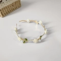 Detalle de diadema dorada con rosas blancas, hojas verdes y perlas en fondo blanco - Flor blanca con hojas verdes