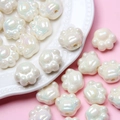 Macro shot of iridescent cat paw acrylic beads for DIY jewelry on a pink background - Off White