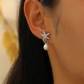Detail view of starfish stud earrings with sparkling pavé stones and pearl drops - Starfish Pearl Style (WG0091) / Silver