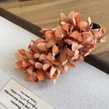Detailed view of peach chiffon flower hair clip with petal texture on fabric board - Orange