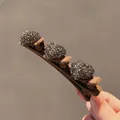 Braune beflockte Haarspange mit drei glitzernden Herz-Strasssteinen in der Hand - Herz Nach Links / Kaffeebraun
