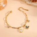Pulsera de mariposa chapada en oro de 18k con circonitas en un suave fondo beige - Estilo Concha Negra y Blanca Dorada (E819)