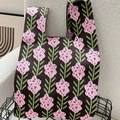 Close-up of knit tote bag with pink flower pattern on a textured cream sofa - Lavender Black & Pink