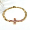 Dettaglio del bracciale a catena dorata con pendente a croce e zirconi rosa - Rosa