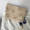 Detail of beige corduroy pouch with black smiley patterns and brand tag on white fabric - Khaki Smiley Face Storage Bag