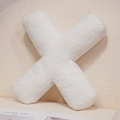 Plush white letter X shaped throw pillow made of soft sherpa fabric on a sofa - Letter X