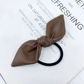Brown leather bow hair tie with black elastic band on a minimalist background - Brown