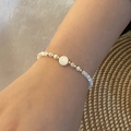 Detailed shot of beaded bracelet with white shell beads and gold letter O pendant - Letter O Style (O)