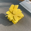 Close-up of a matte yellow flower hair claw clip on a textured background - Yellow