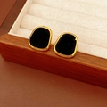Vue détaillée des boucles d'oreilles dorées ovales avec velours noir sur présentoir - Carré / Noir
