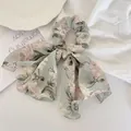 Detail of floral chiffon hair scrunchie with long ribbon on a decorative white plate - Green Floral With Trim