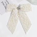 Close-up of white ribbon bow hair clip with faux pearls and sparkling rhinestone centerpiece - Off-white