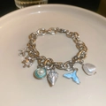 Detailopname van een zilverkleurige armband met zeester en parels in maritieme stijl - Zilveren Zeester Wulk Armband