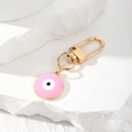 Close-up of pink Evil Eye keychain with gold alloy lobster clasp on white stone - Pink