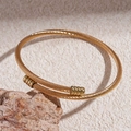 Macro-opname van een gouden gedraaide kabelarmband met metalen cilindrische doppen - Goud