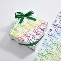 White birthday gift wrapping paper with rainbow lettering and a dark green ribbon bow - Colorful Letters