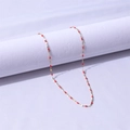 Dettaglio di una sottile collana in acciaio inossidabile dorato con piccole perline rosse - Oro+Rosso / 45+5cm