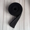 Detail of a black wool belt roll with reinforced stitching on a grey wooden surface - Black