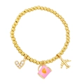 Bracelet en perles dorées avec breloques cœur, tasse rose et avion sur fond blanc - Rose