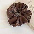 Close-up of brown paisley print scrunchie resting on a vintage book edge - Basic Style / Coffee