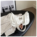 Detail shot of a white pleated underarm bag featuring a silver butterfly buckle - White