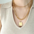 Three-layer gold necklace set featuring geometric pendant with abstract body art on sweater - Gold 3-Layer Necklace
