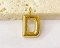 Macro shot of a chunky gold metal bubble pendant in letter D shape on stone surface - Letter-D / Steel