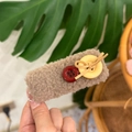 Close-up of brown teddy fur hair clip featuring decorative red and yellow buttons - Khaki