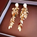 Primer plano detallado de pendientes largos de lentejuelas doradas en joyero elegante - Pendientes de borla de lentejuelas de hoja dorada