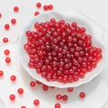 Vibrant transparent red 6mm round glass beads in a decorative white shell bowl - Transparent Red Chalcedony Beads (6mm)