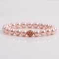 Bracciale di perle rosa con charm traforato in oro rosa su superficie a specchio bianca - Rosa