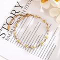 Detailed shot of white enamel daisy charms on golden stainless steel chain bracelet - White