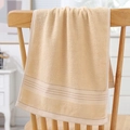 Thick beige cotton towel with horizontal stripes hanging on a wooden chair - Cotton Gold Ribbon Cream (Towel)