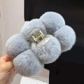 Detailed close-up of a large grey-blue plush hair claw clip with soft faux rabbit fur balls - Gray