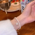Double-layer pearl bracelet featuring a white camellia flower charm in golden finish - Double Layer Pearl Camellia Bracelet