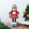 Dettaglio di un pinguino natalizio con cappello in maglia e gonna a quadri vicino all'albero - Pinguino con gambe telescopiche e cappello grigio