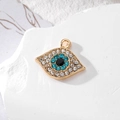 Macro view of gold devil eye pendant with blue and white crystals on stone base - Gold Pointed Sky Blue Eye