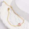 Détail du bracelet plaqué or avec zircon ovale rose sur un plateau plume blanc - Rose