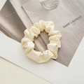 Gros plan détaillé d'un chouchou en satin crème avec texture soyeuse sur magazine - Nouveau Blanc Crème