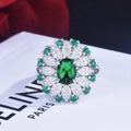 Detail shot of a flower-shaped ring with emerald green center stone and diamond accents - Green Zirconia / Adjustable Open